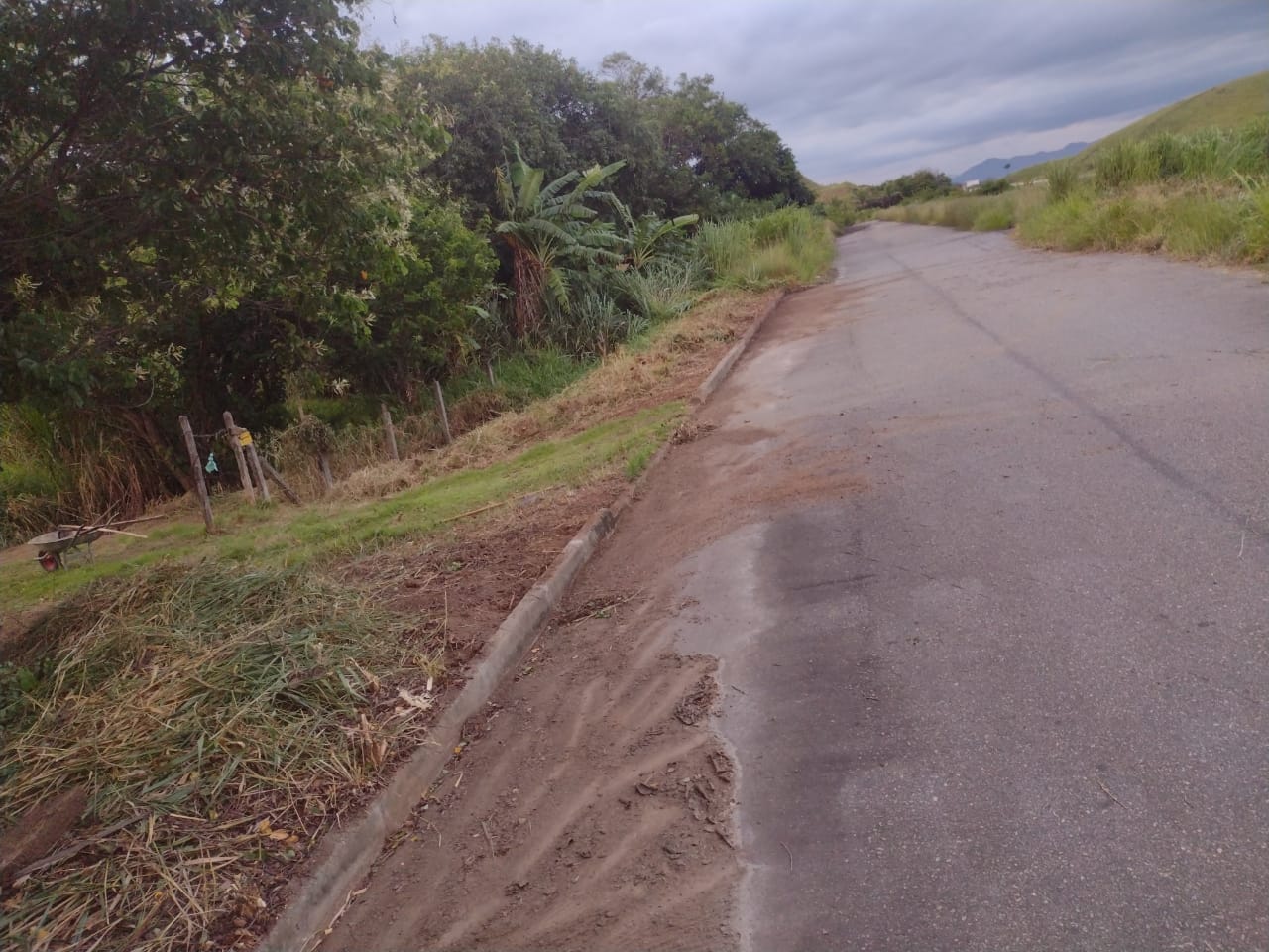 Rua asfaltada no nível da rodovia, na frente do terreno